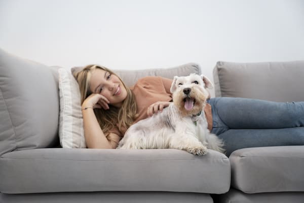 mulher sorridente com foto media e cachorro no sofa